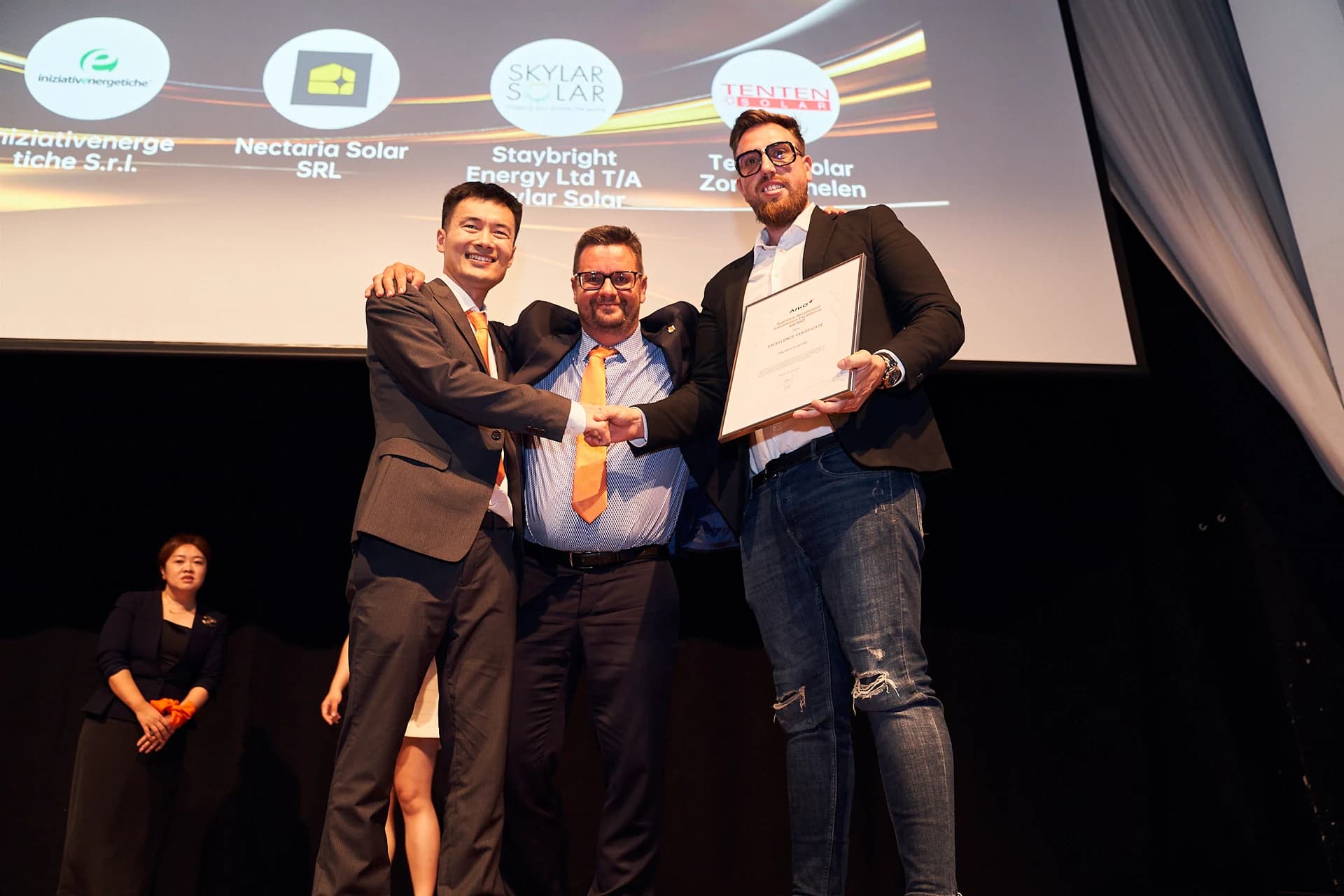 Reprezentanții Nectaria Solar la gala AIKO, cu certificatul Supreme Residential Installation Excellence Award 2024 și numele companiei pe ecran